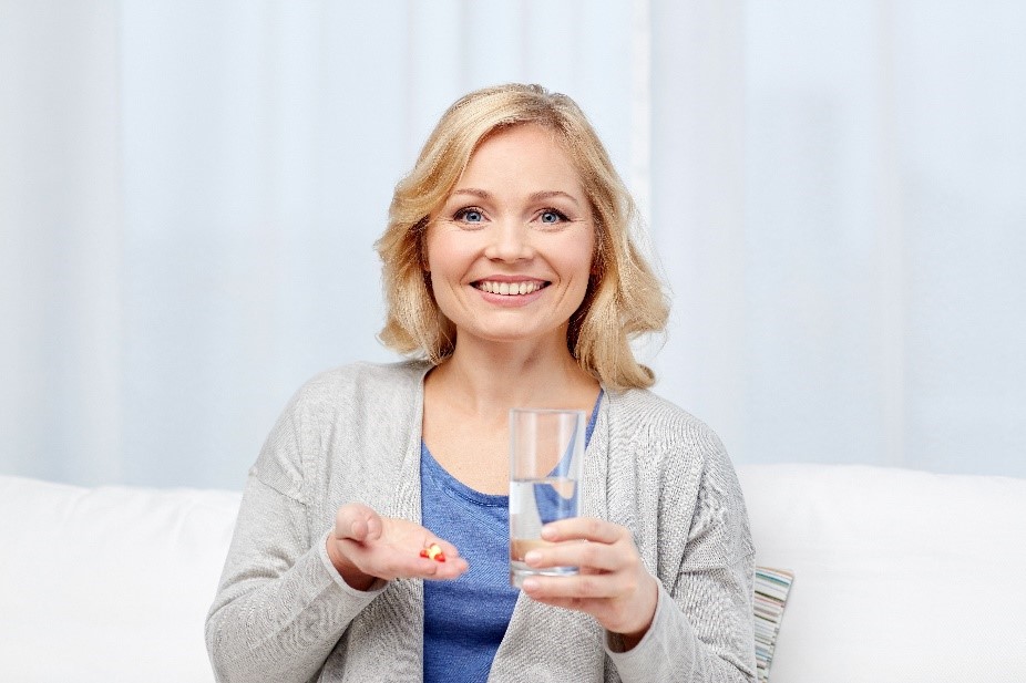 Smiling woman preparing to take her nutritional eye supplements