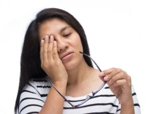 woman with possible eye infection rubbing her eye in pain